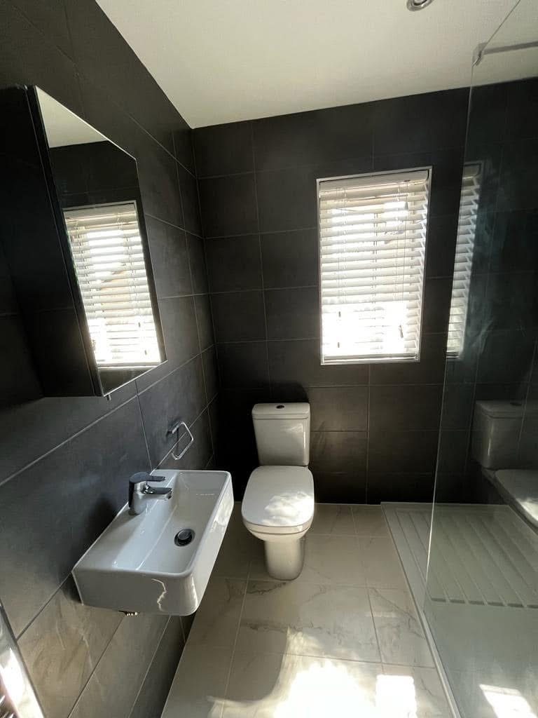 Reinstated bathroom with dark porcelain tiling, walk-in shower and modern wall-hung sanitaryware
