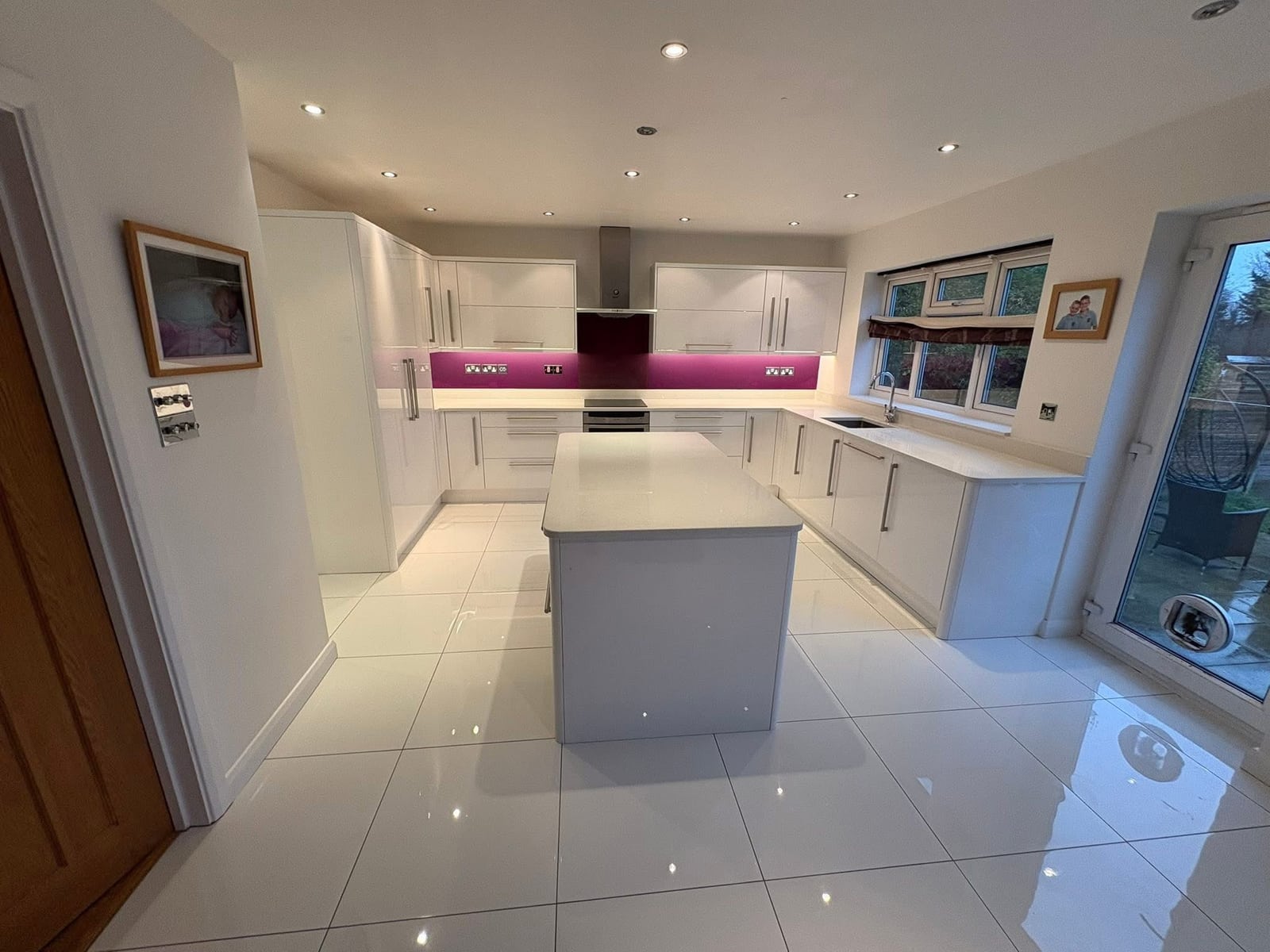 New U-shape kitchen with island, magenta glass splashback and integrated double oven