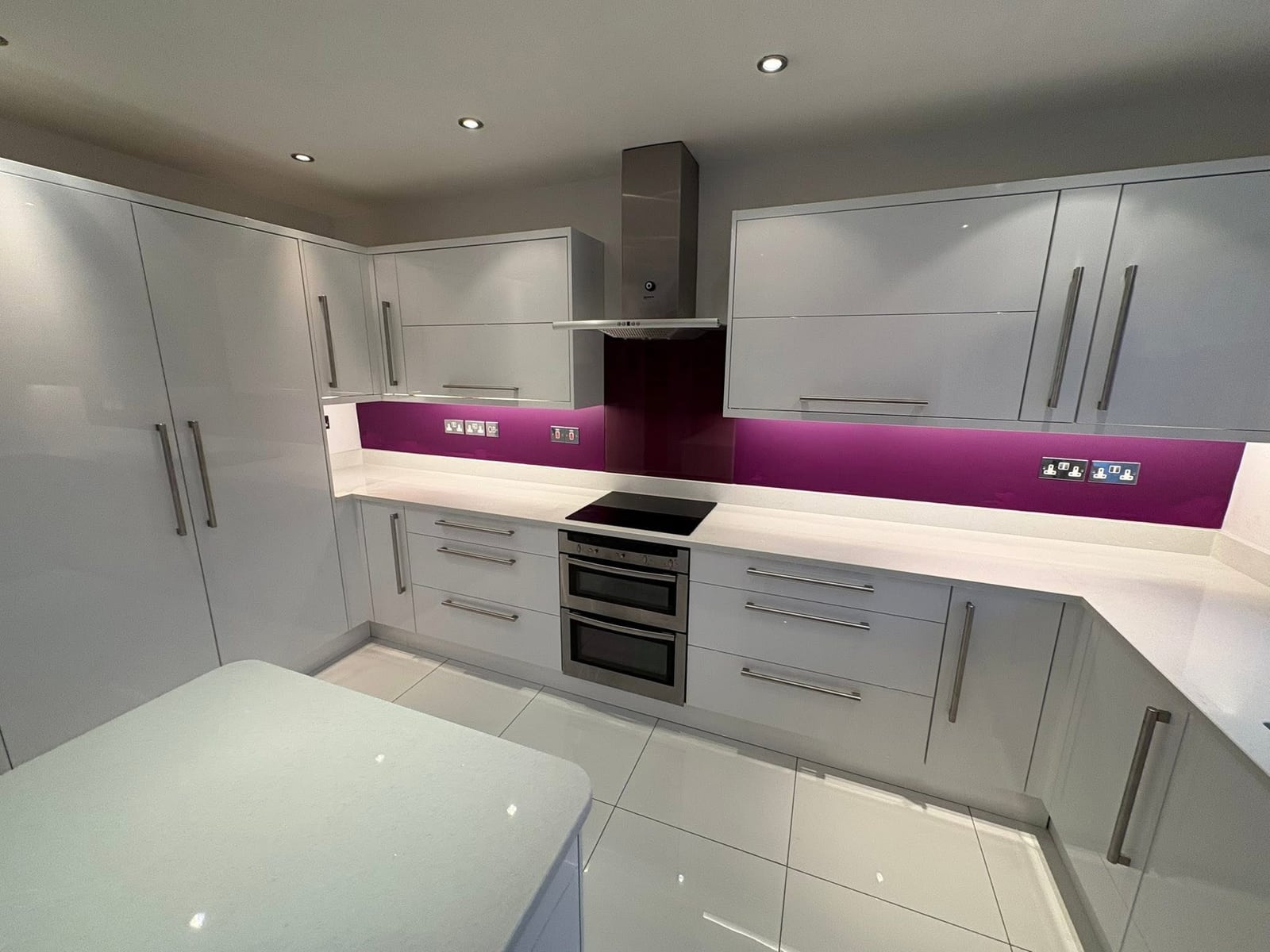 Fitted corner cabinetry with integrated double oven and gloss splashback