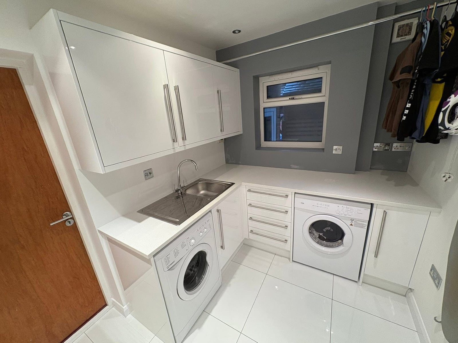 Newly fitted utility room with white cabinetry, sink and integrated washing machine