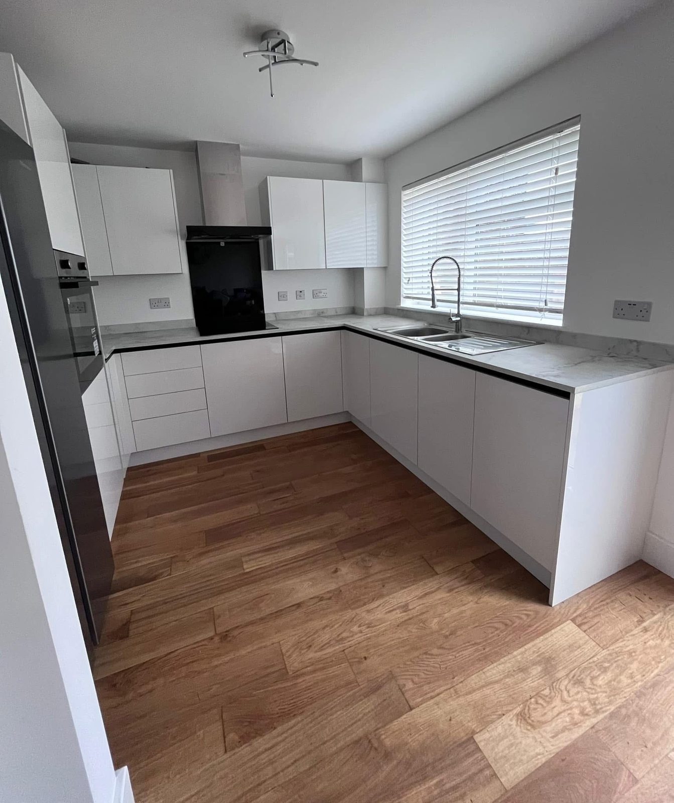 New U-shape kitchen with handleless white cabinetry and marble-effect worktops