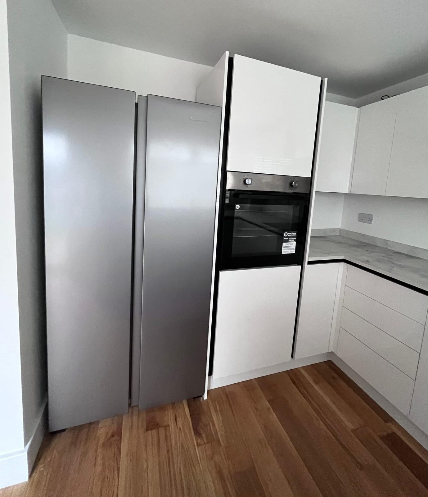 New kitchen detail showing built-in oven, integrated fridge-freezer and gloss finish